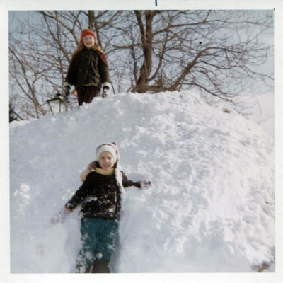 A picture of the author as a young boy standing in front of a very large snowbank and his sister standing atop it in the 1970s.